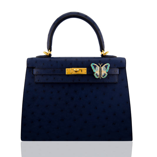 Navy handbag with gold hardware and a butterfly emblem on a white background, collection-preview