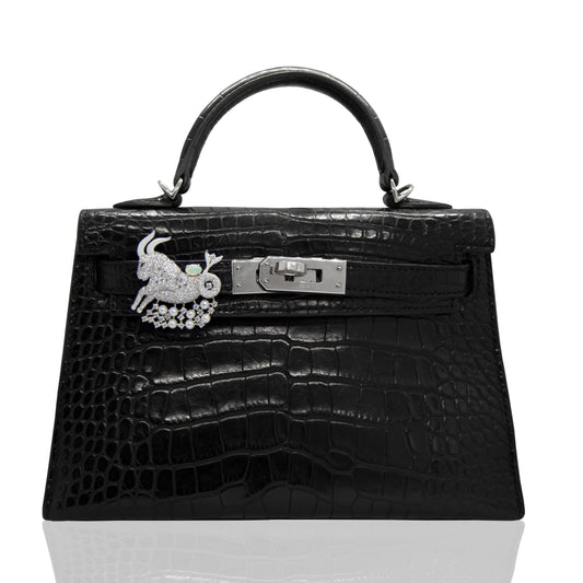 Black crocodile skin handbag with a decorative clasp on a white background, collection-preview