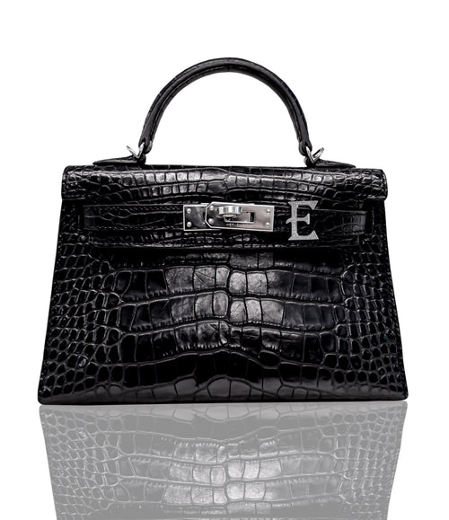 A black handbag with a crocodile pattern, featuring a metallic clasp and a leather handle, collection-preview.