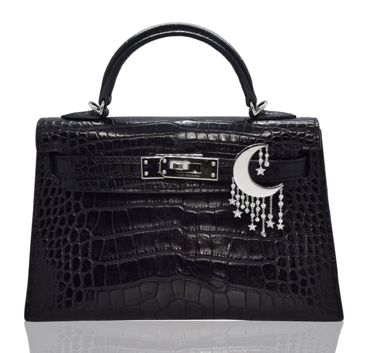 Black textured handbag with moon and star accessory on a white background, collection-preview