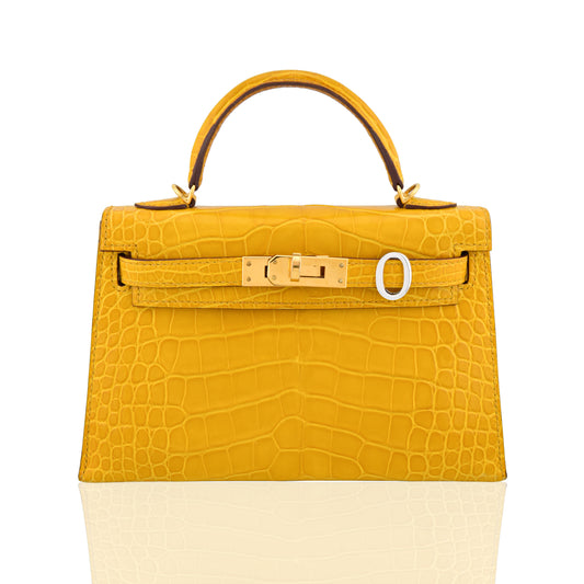 Yellow crocodile-patterned handbag with a gold buckle on a white background, collection-preview
