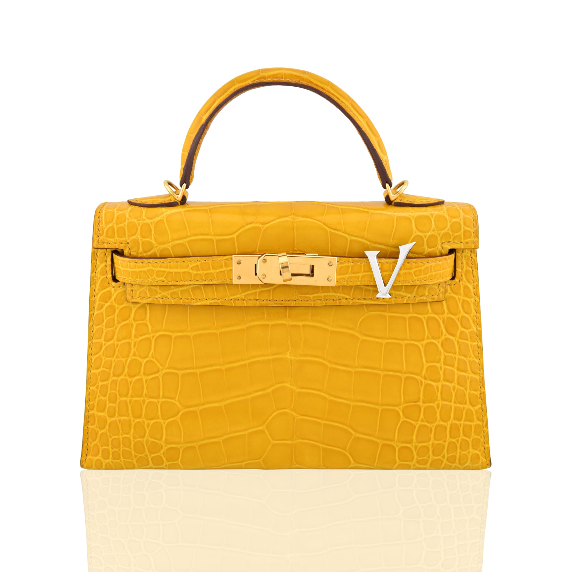 Yellow crocodile skin handbag with gold hardware on a white background, collection-preview