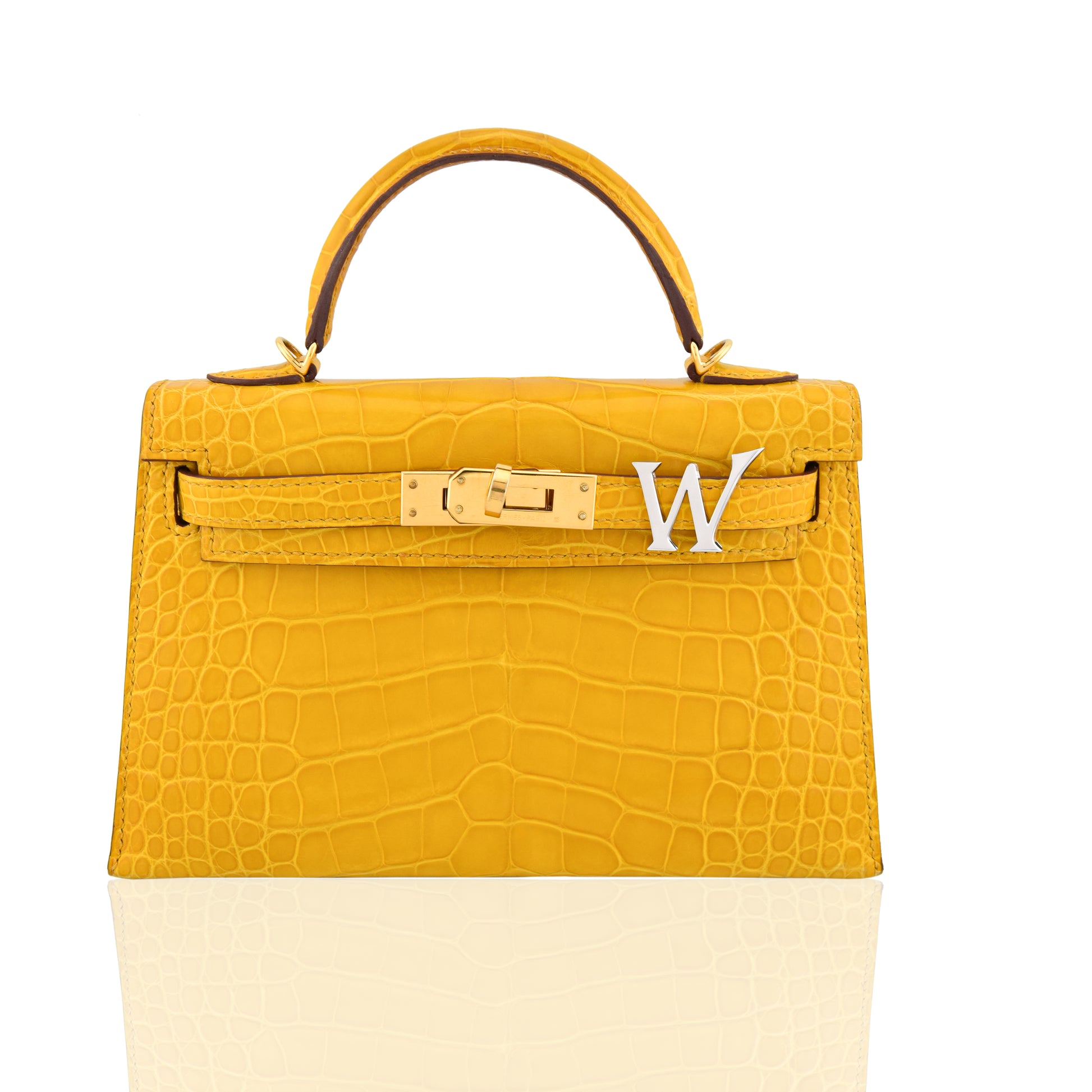 Yellow crocodile-patterned handbag with a gold clasp and white letter 'W' on a white background, collection-preview