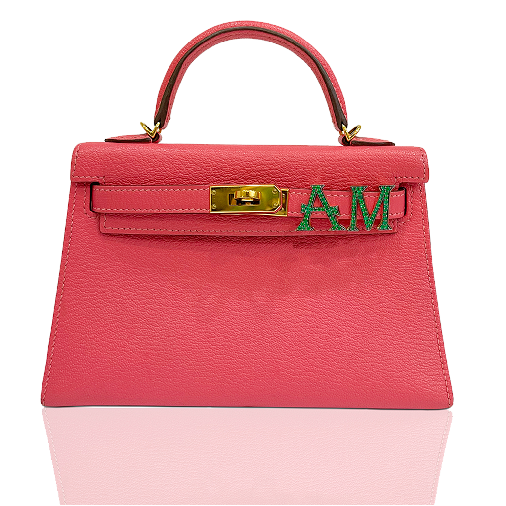 Pink handbag with gold clasp and green letters on a white background, collection-preview
