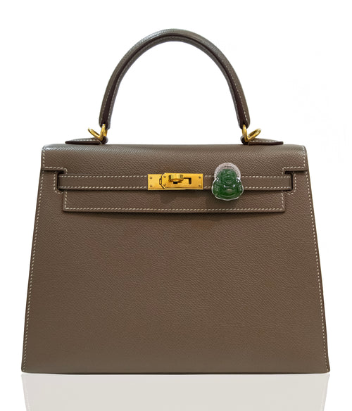 Brown handbag with gold hardware and a green clasp on a white background, collection-preview