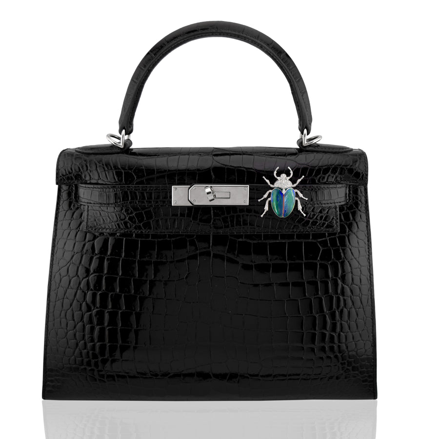 Black crocodile skin handbag with silver hardware and a decorative beetle pin on a white background, collection-preview