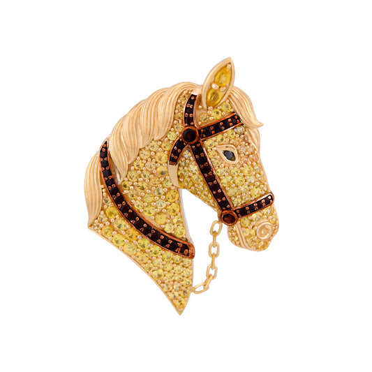 Gold horse head brooch with gemstones on a white background