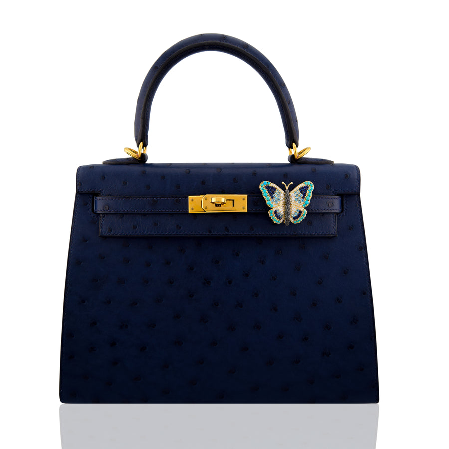 Navy handbag with gold hardware and a butterfly emblem on a white background, collection-preview