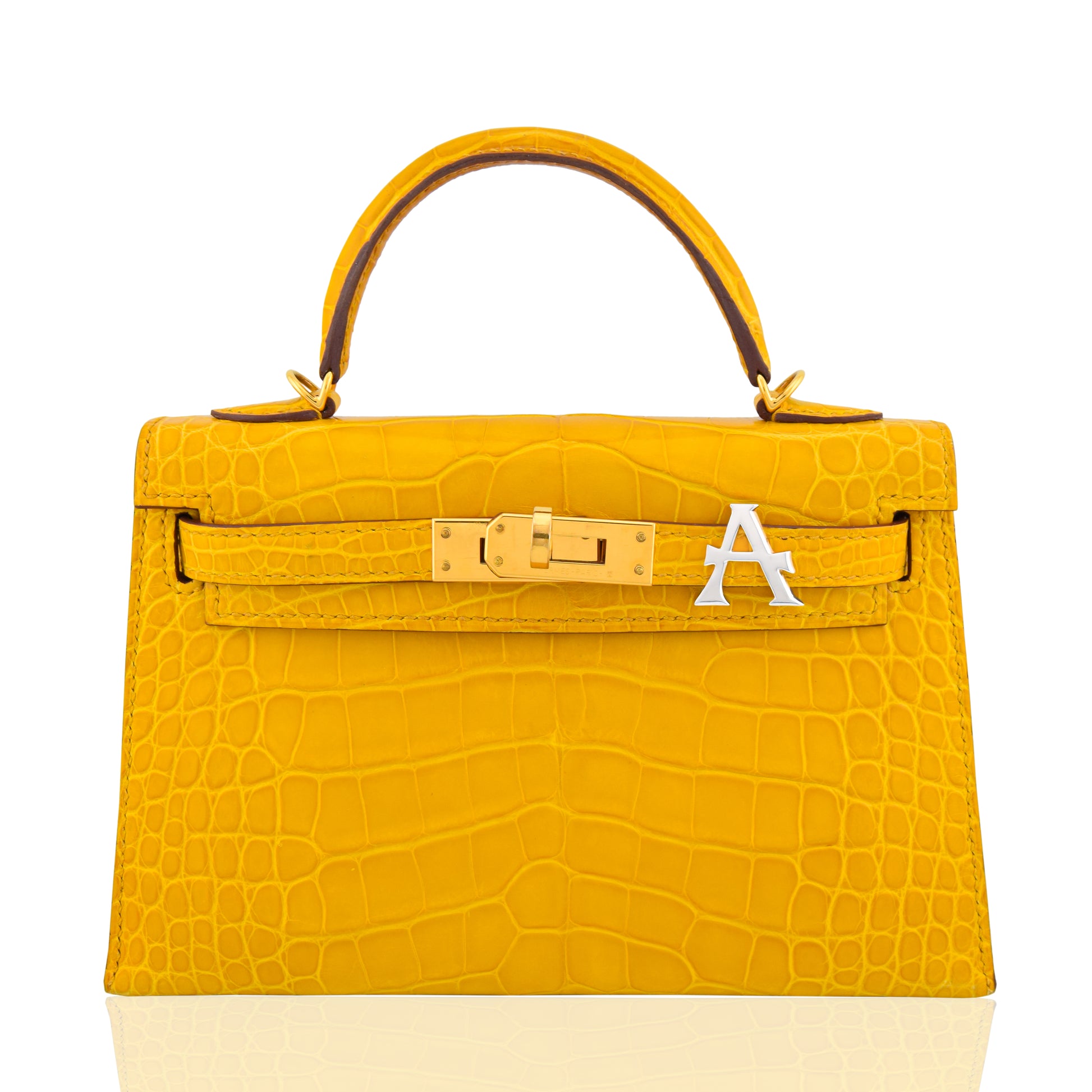 Yellow crocodile skin handbag with gold hardware and a white logo on a white background, collection-preview