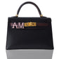 Black handbag with gold hardware and pink and gold 'AM' initials on a white background, collection-preview