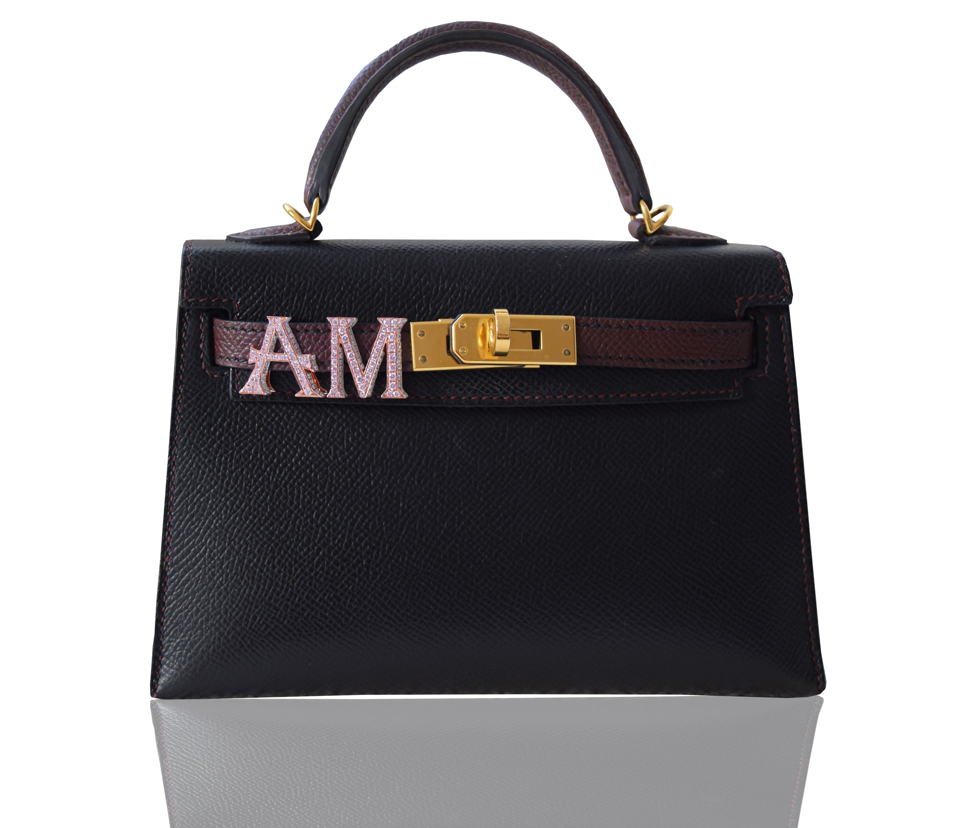 Black handbag with gold hardware and pink and gold 'AM' initials on a white background, collection-preview