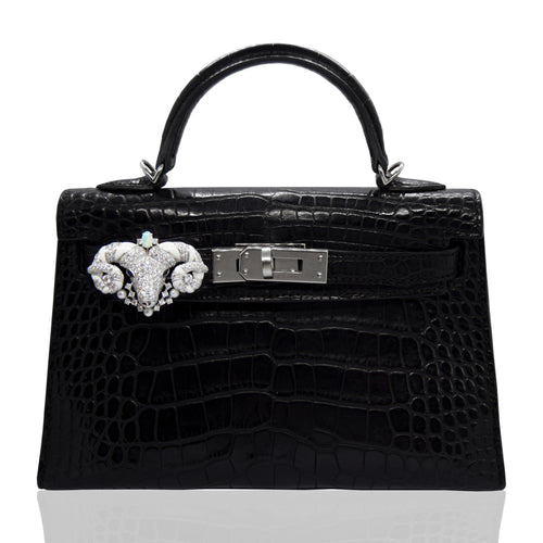 Black crocodile skin handbag with decorative clasp on a white background, collection-preview
