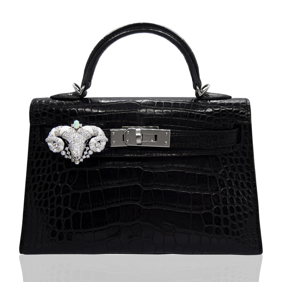 Black crocodile skin handbag with decorative clasp on a white background, collection-preview