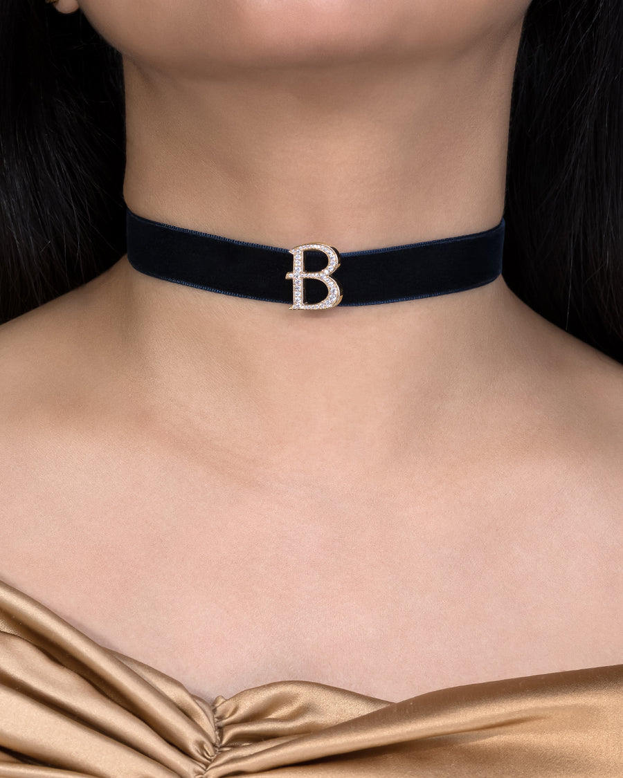 Navy velvet choker with a decorative 'B' clasp worn by a person.