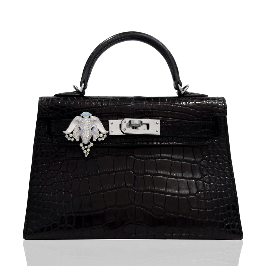 Black crocodile skin handbag with a decorative clasp on a white background, collection-preview