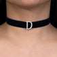 Black choker necklace with a silver 'D' clasp on a person's neck.