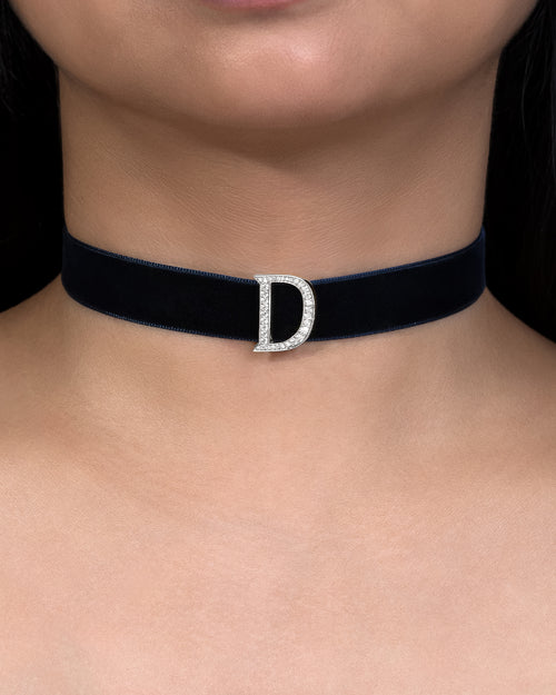 Black choker necklace with a silver 'D' clasp on a person's neck.