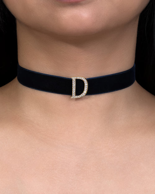 Black choker with a diamond 'D' clasp on a person's neck