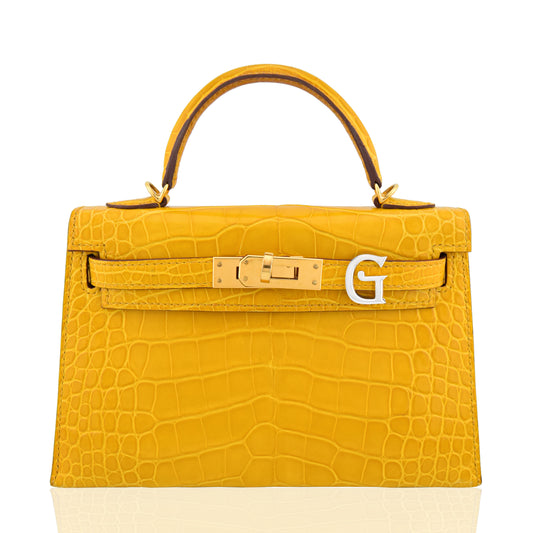 Yellow crocodile-patterned handbag with gold hardware on a white background, collection-preview
