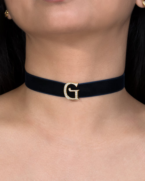 Navy blue choker with a gold 'G' clasp worn by a person