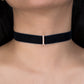 Black choker with a small diamond clasp on a person's neck against a black background