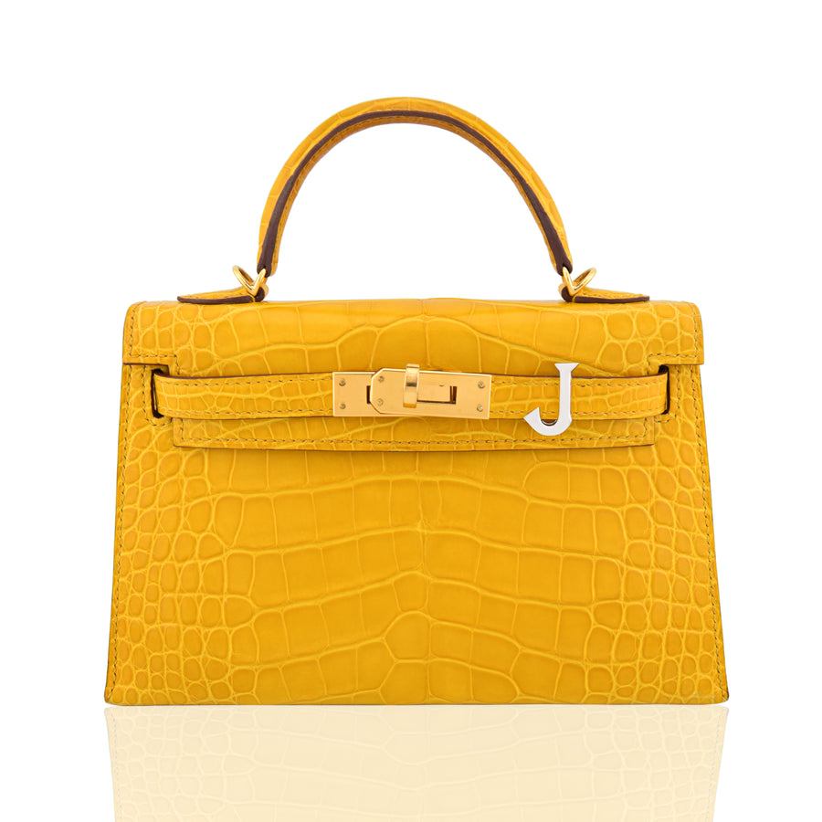 Yellow crocodile-patterned handbag with gold hardware on a white background, collection-preview