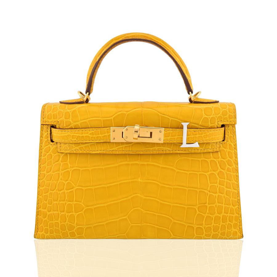 Yellow crocodile skin handbag with gold hardware on a white background, collection-preview
