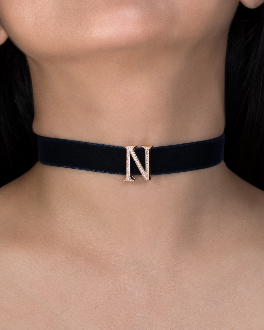Black choker necklace with a letter 'N' pendant on a person's neck.