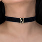 Black choker necklace with a gold letter 'N' on a person's neck