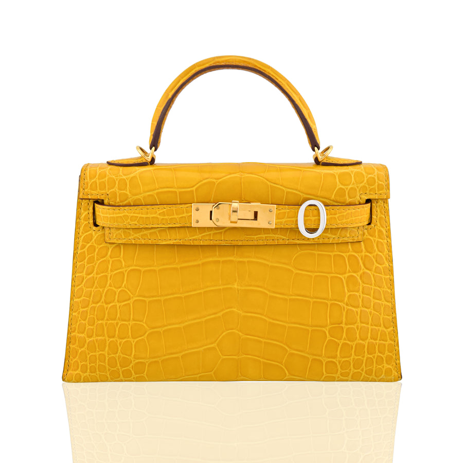 Yellow crocodile-patterned handbag with a gold buckle on a white background, collection-preview