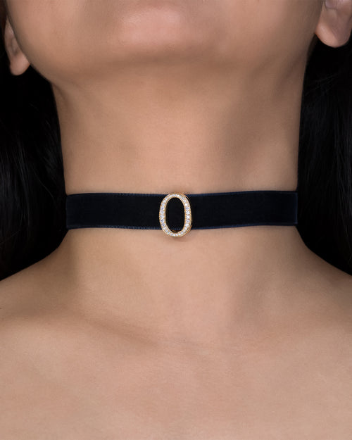 Black choker with a gold buckle worn by a person against a dark background