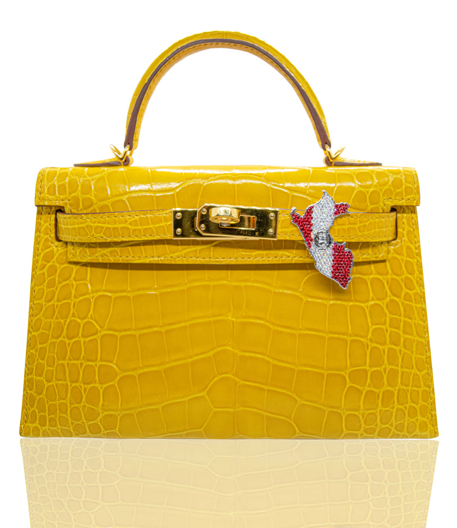 A yellow handbag with a crocodile pattern featuring abijoux accessory with Peru flag attached to it, collection-preview.