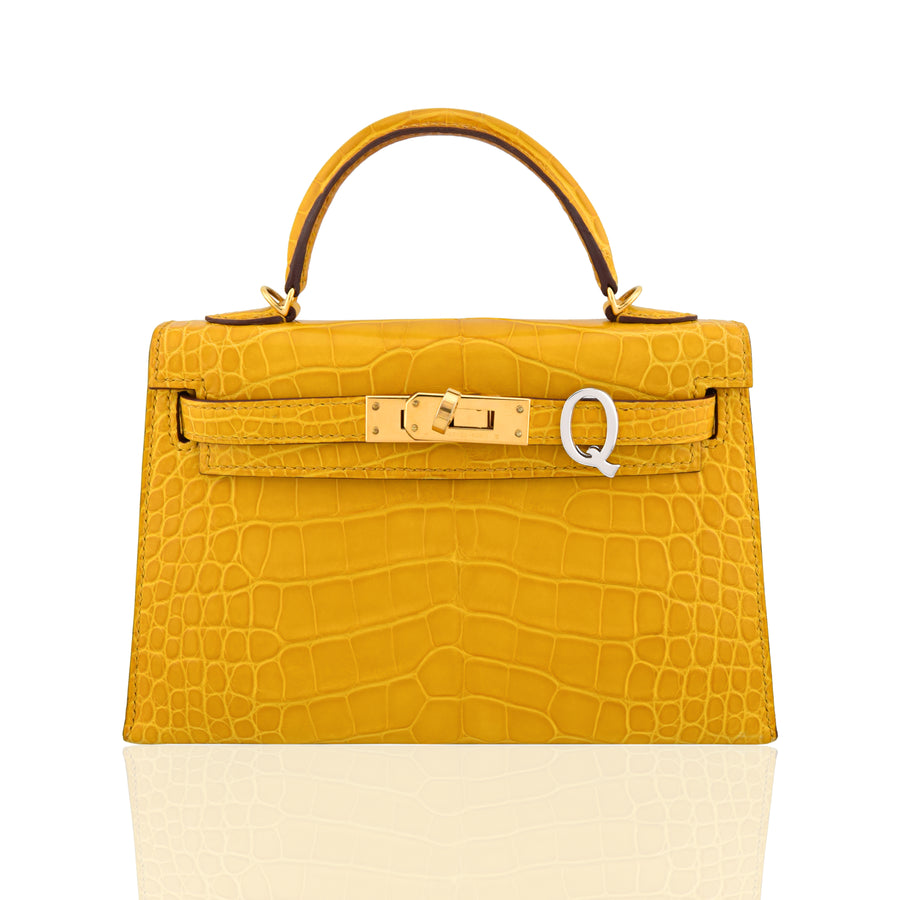 Yellow crocodile-patterned handbag with a gold clasp on a white background, collection-preview