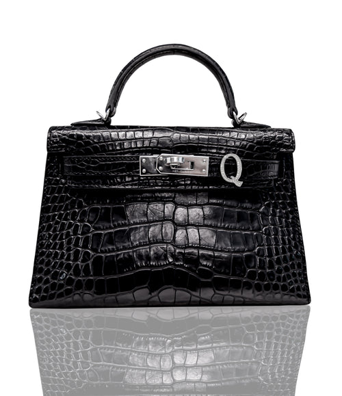 A black handbag with a crocodile pattern and a metallic clasp, resembling a Birkin bag, collection-preview.