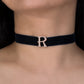 Navy blue choker with a rose gold 'R' on a person's neck