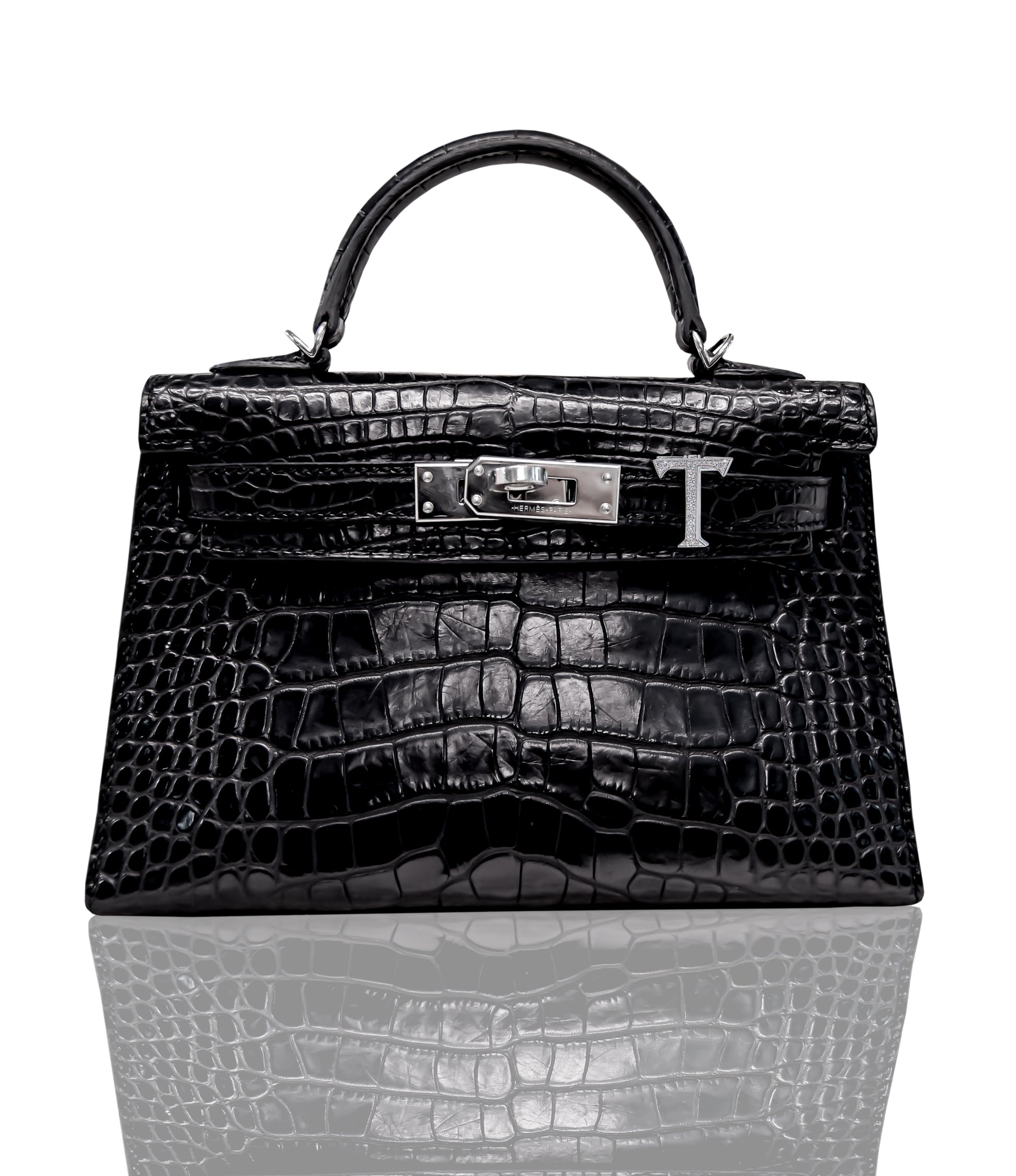 A black handbag with a crocodile pattern and a metallic 'T' closure, collection-preview.