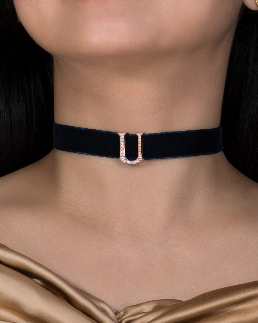 Black velvet choker with a silver buckle on a model wearing a gold top.