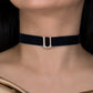 Black velvet choker with a silver clasp on a person wearing a gold top.