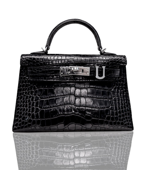 A black handbag with a crocodile pattern and a metallic clasp, resembling a luxury brand like Hermès, collection-preview.