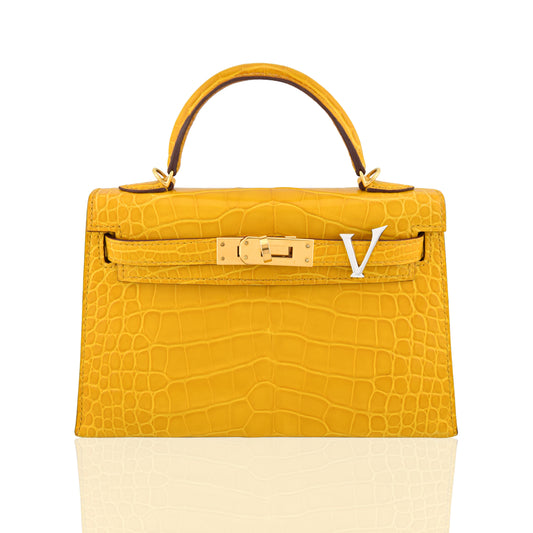 Yellow crocodile skin handbag with gold hardware on a white background, collection-preview