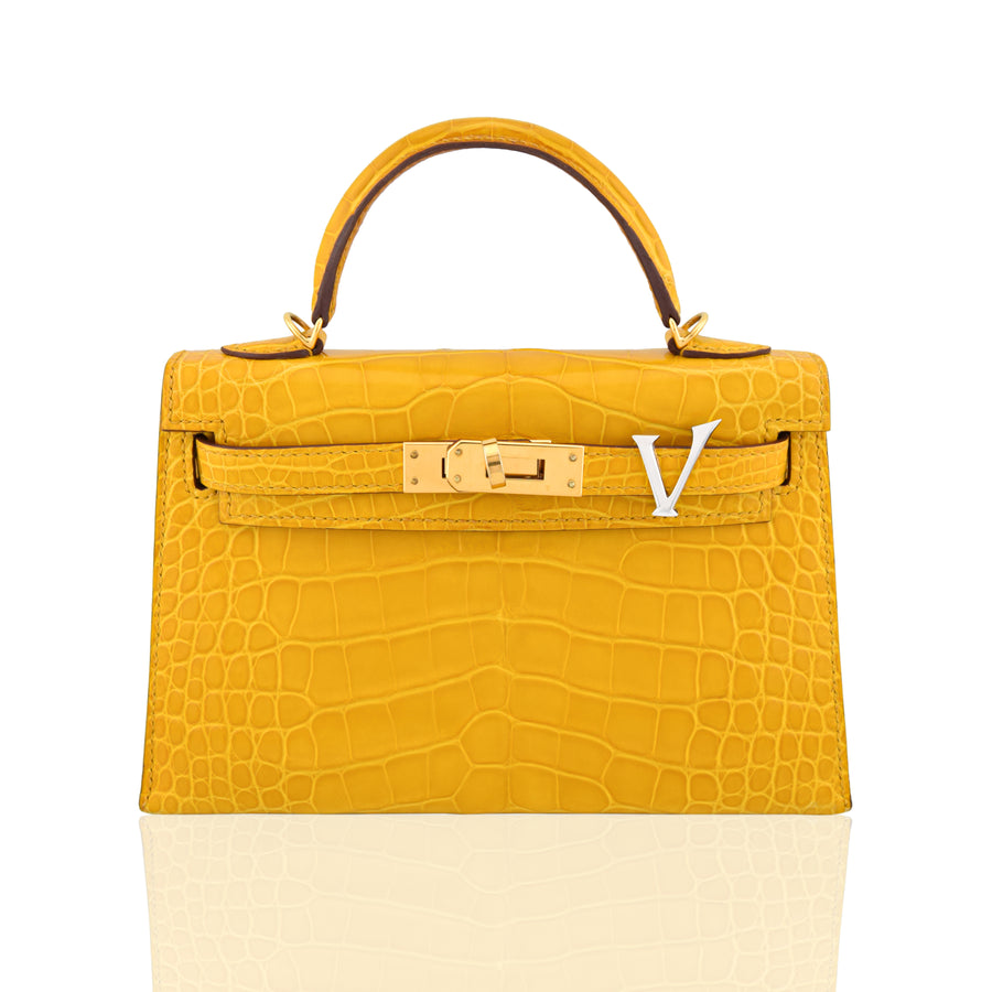 Yellow crocodile skin handbag with gold hardware on a white background, collection-preview