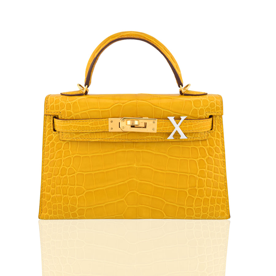 Yellow crocodile skin handbag with gold hardware on a white background, collection-preview