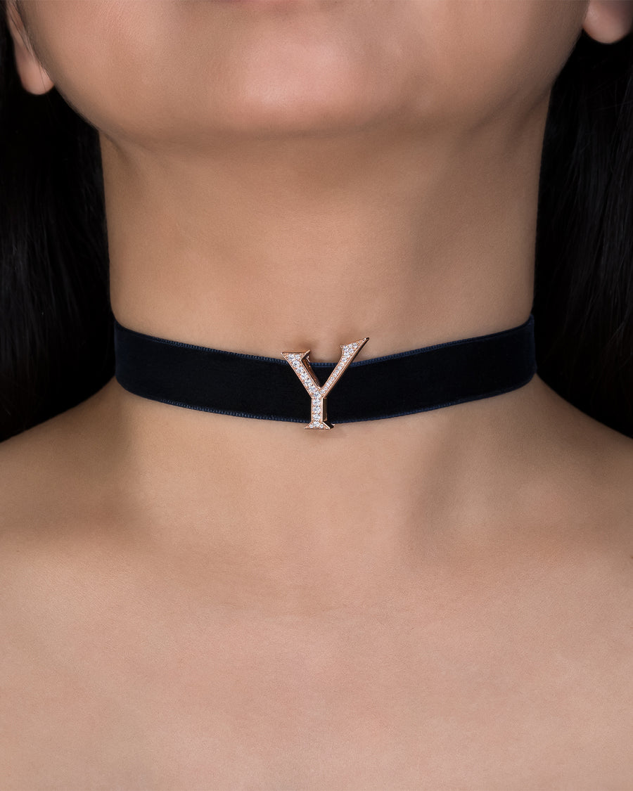 Black choker necklace with a gold 'Y' pendant on a person's neck.