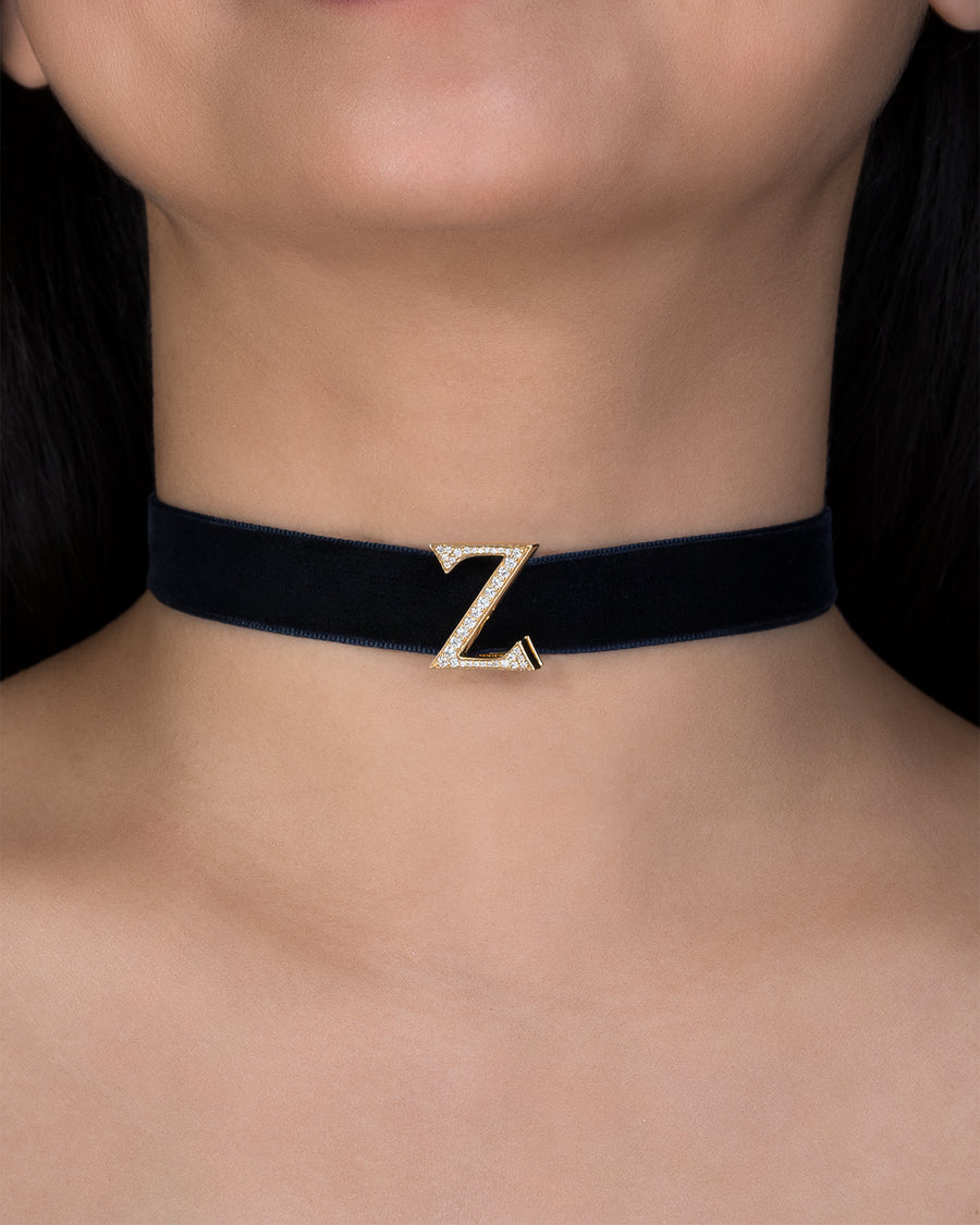 Black choker necklace with a gold 'Z' clasp on a person's neck