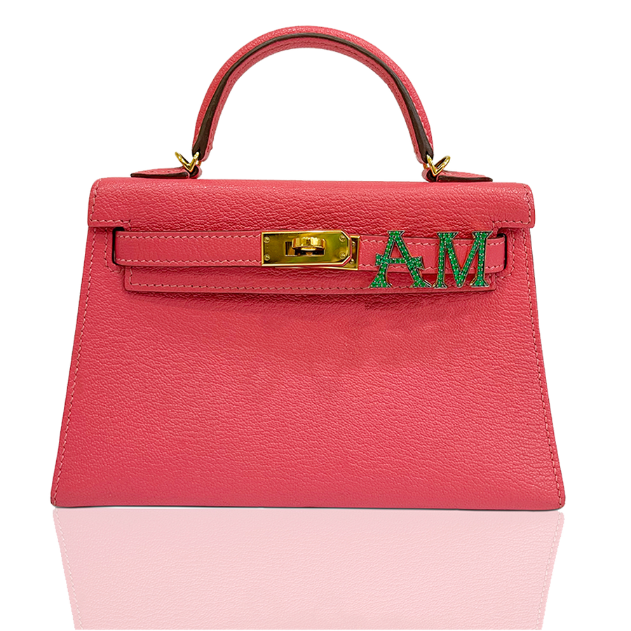 Pink handbag with gold clasp and green letters on a white background, collection-preview
